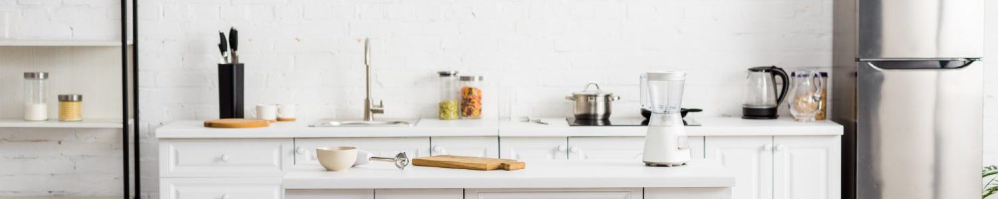 modern white kitchen with table and kitchenware and fridge